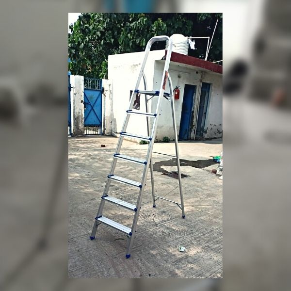 1 An aluminium ladder resting on the ground outdoors.